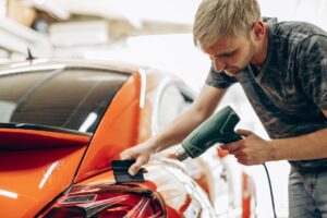 Vehicle receiving protective foil wrap while drying with fan at car detailing service