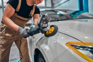 Detailer using rotary polisher on white car for smooth and glossy finish