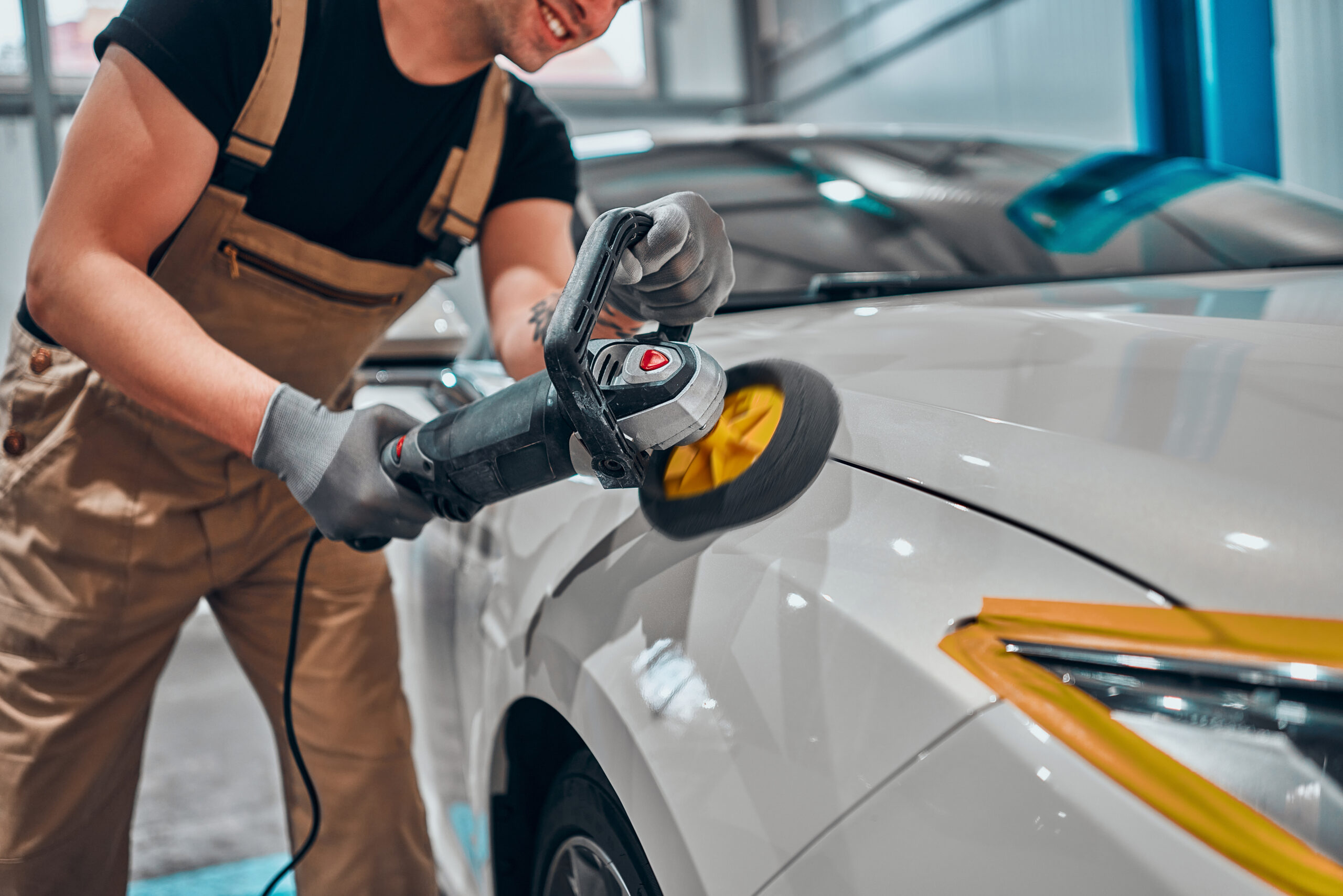 Detailer using rotary polisher on white car for smooth and glossy finish