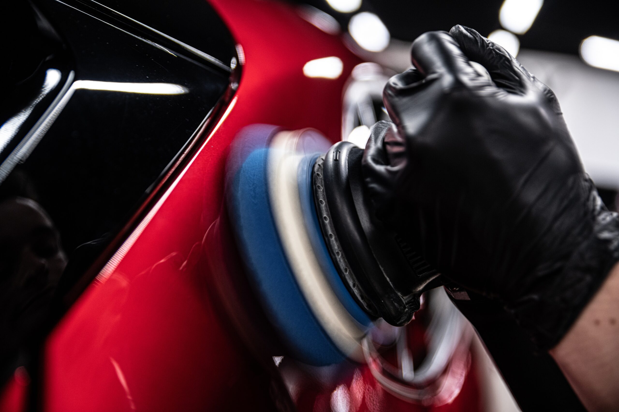 Car paint surface being corrected with electric polishing machine at detailing studio